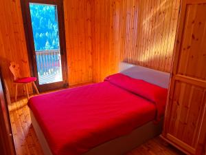 a bedroom with a red bed and a window at Dolomites View Apartment - Mountain Relax Experience in Cibiana