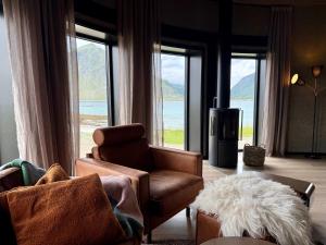 a living room with a couch and chairs and windows at Flakstad beach house Silo A in Vareid