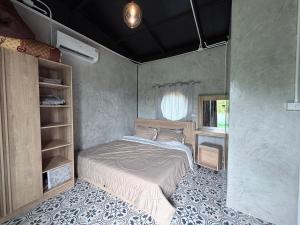 a small bedroom with a bed and a window at ภูหลงหมอก รีสอร์ท in Ban Huai Lat