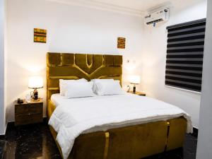a bedroom with a large bed with white sheets and two lamps at Aaron Obibi Court in Owerri