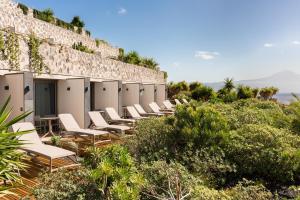 a row of white chairs lined up against a wall at BANCAL HOTEL and SPA in San Sebastián de la Gomera