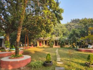 a yard with trees and a house in the background at Saiesh resort in Alibaug