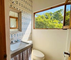 a bathroom with a toilet and a sink and a window at Villa Poesía in Puerto Escondido +43 photos