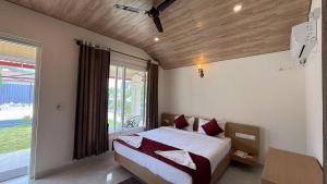 a bedroom with a bed and a large window at Chirooss Homestays And Resorts in Chikmagalūr