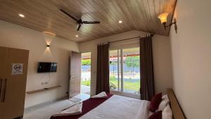 a bedroom with a bed and a tv and a window at Chirooss Homestays And Resorts in Chikmagalūr
