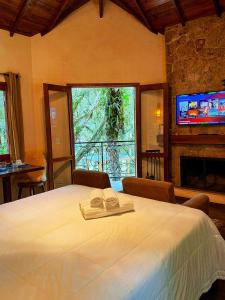 a bedroom with a bed and a large window at Chalés Montanha Serrana - Monte Verde in Monte Verde