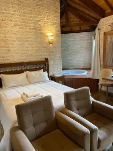 a bedroom with a bed with a chair and a tub at Chalés Montanha Serrana - Monte Verde in Monte Verde +41 photos