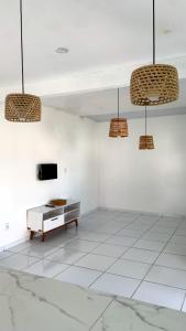 a room with a tv and a table and pendant lights at Casa Arembepe in Camaçari