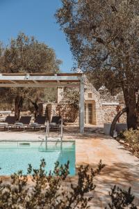 a pool with a pergola next to a house at Trullo Serenità Charming Trullo with Private Pool in Apulië in Ceglie Messapica