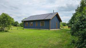 a small blue house in a grassy field at Kaasaegne puhkemaja in Kersalu