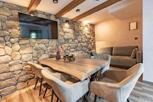 a dining room with a stone wall and a wooden table and chairs at Kuća za odmor Šum slapa in Karlovac