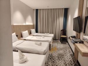 a hotel room with three beds and a flat screen tv at فندق بشاير الإجابة Bashaier Al EJaba Hotel in Mecca +42 photos