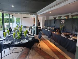 a dining room with a long table with black tables and chairs at Riebeek Valley Hotel in Riebeek-Wes +14 photos
