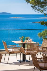 a table and chairs on a patio with a view of the ocean at Aminess Alfir Hotel in Blato +69 photos