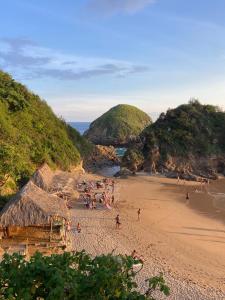 a group of people on a beach with mountains at Zipolite Maracuya Hostel & Rooms in Zipolite