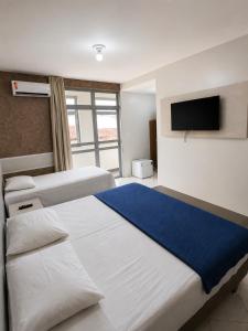 a bedroom with two beds and a flat screen tv at Hotel Executivo formosa in Formosa +6 photos