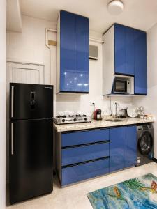 a kitchen with blue cabinets and a black refrigerator at Tahrir Residence -"Marriage Certificate Required for Couples" in Cairo