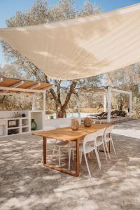 a wooden table and chairs under a tent at Trullo Serenità Charming Trullo with Private Pool in Apulië in Ceglie Messapica