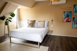 a bedroom with a bed with white sheets and pillows at Hotel de Wereld in Wageningen