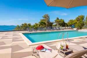 a swimming pool with chairs and an umbrella at Aminess Alfir Hotel in Blato