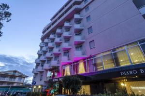 アルバ・アドリアティカにあるHotel Principeのピンクの灯りをかぶった高層ビル