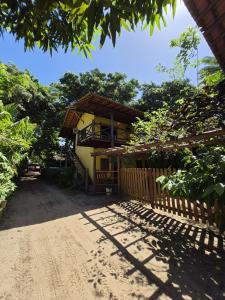 a house with a fence in front of a dirt road at Pousada Encanto do Mutá in Barra Grande