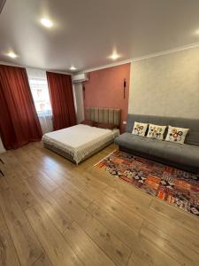 a bedroom with a bed and a couch and a rug at Апартаменты в центре in Balqash