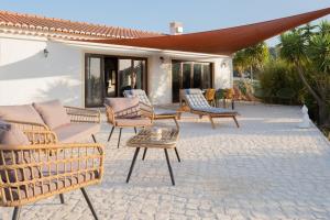 a patio with wicker chairs and a table at Vida Pura Guesthouse in Odeceixe