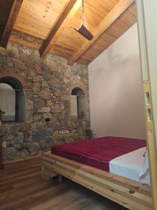 a bedroom with a bed in a stone wall at Kulla Zefit Agritourism in Hajmel