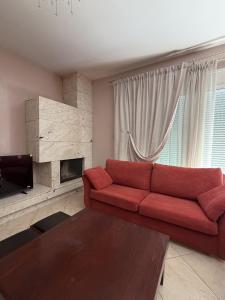 a living room with a red couch and a fireplace at Kali's home in Komotini