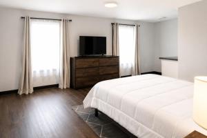 a bedroom with a bed and a flat screen tv at Spacious Private Queen Studio Near Downtown in Muskegon