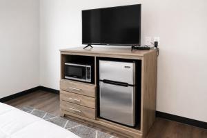 a tv on a wooden stand with a refrigerator and a microwave at Cozy Updated Queen Ground Floor Studio in Muskegon