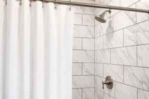 a shower with a shower curtain and a shower head at Cozy Updated Queen Ground Floor Studio in Muskegon +22 photos