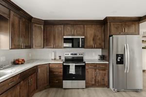 a kitchen with wooden cabinets and a stainless steel refrigerator at New! Cozy Family Getaway: Amish Farmland|Patio|Washer & Dryer|Central Lancaster County in Ronks
