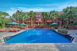 a pool with chairs and umbrellas in front of a building at ITC Mughal, A Luxury Collection Resort & Spa, Agra in Agra