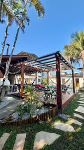 a wooden pavilion with picnic tables and palm trees at Makai Suites in Ubatuba