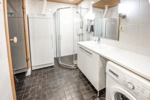 a bathroom with a shower and a sink and a washing machine at Ruka Ski Chalets in Ruka +49 photos
