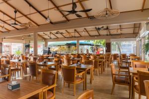 a restaurant with wooden tables and chairs at Triton Exotica in Maafushi