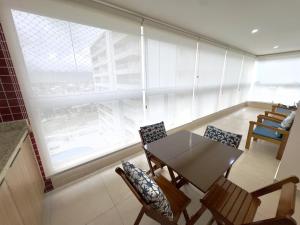 a dining room with a table and chairs and a large window at San Martin in Bertioga +25 photos