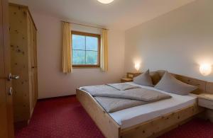 a bedroom with a wooden bed with a window at Ferienhof Blaas in Malles Venosta