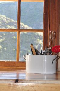 a container of utensils sitting in front of a window at Schuilhoek Cottage - Your perfect hide away! in Calitzdorp