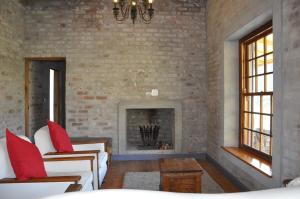 a living room with a brick wall and a fireplace at Schuilhoek Cottage - Your perfect hide away! in Calitzdorp +18 photos