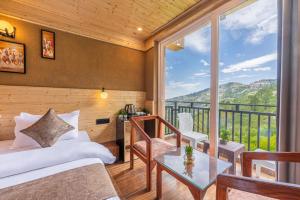a bedroom with a bed and a table and a balcony at The Countryside Retreat I MICE I Vacations I Conference I Family Events I Open Air Terrace I Sky Bonfire I Kufri Shimla by Exotic Stays in Shimla