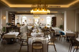 a restaurant with white tables and chairs and a chandelier at Heritage hotel Santa Lucia in Split