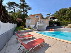 a patio with two chairs and a swimming pool at Villa à Pyla-sur-Mer avec piscine in La Teste-de-Buch