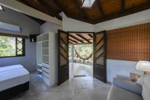 a bedroom with a bed and a couch and a door at Hospedaria Nativa in Praia do Rosa +207 photos