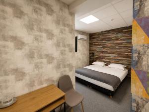 a bedroom with a bed and a table and a chair at Zen Rooms in Suceava