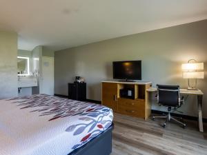 a hotel room with a bed and a desk and a television at Colonial Brick Inn & Suites in New Milford