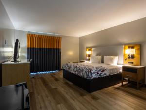 a hotel room with a bed and a television at Colonial Brick Inn & Suites in New Milford