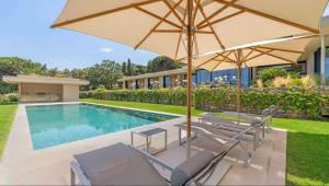 a swimming pool with two chairs and an umbrella at Villa Trois-Pins in Ramatuelle